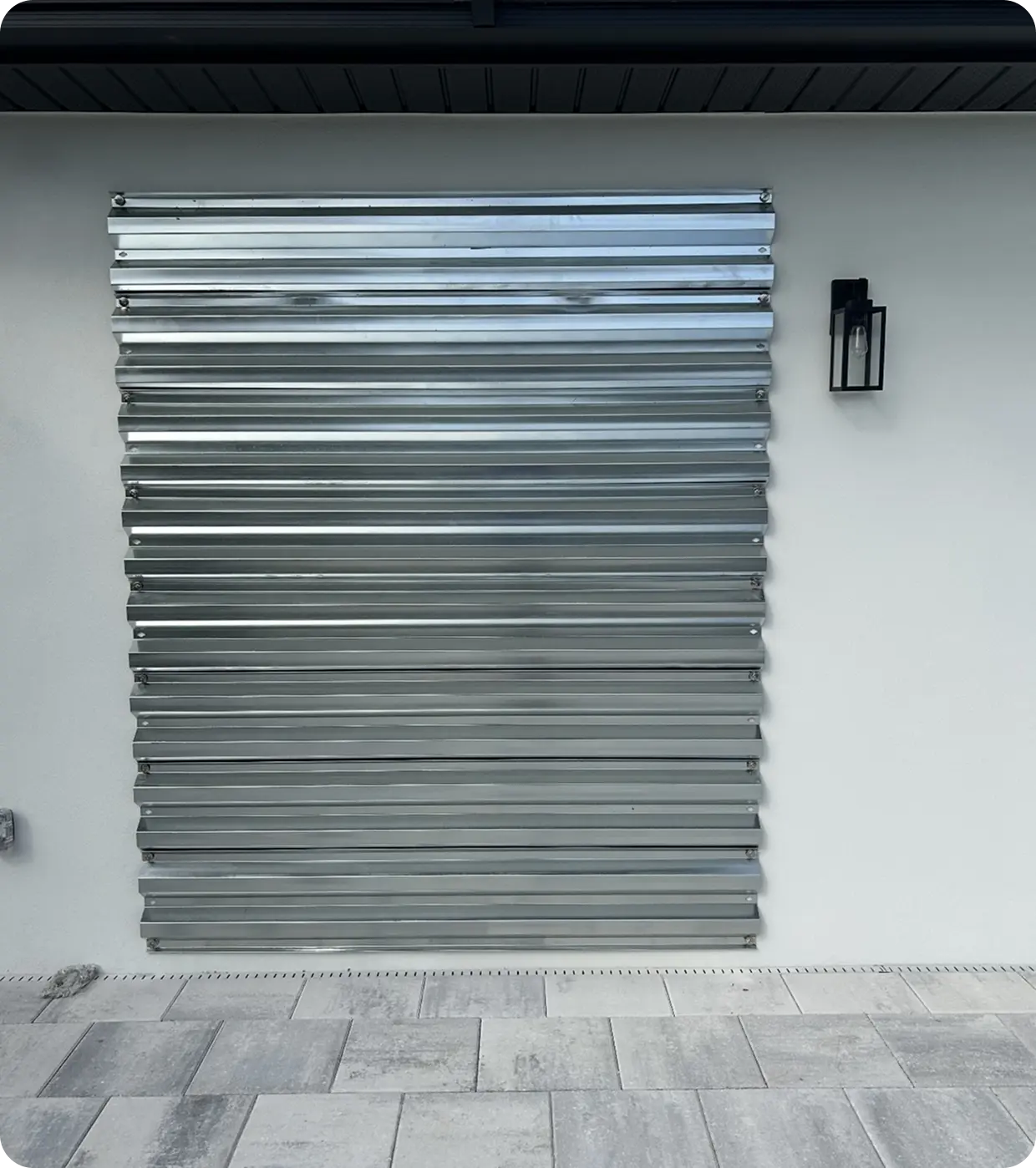 Metal storm shutter on white house wall.